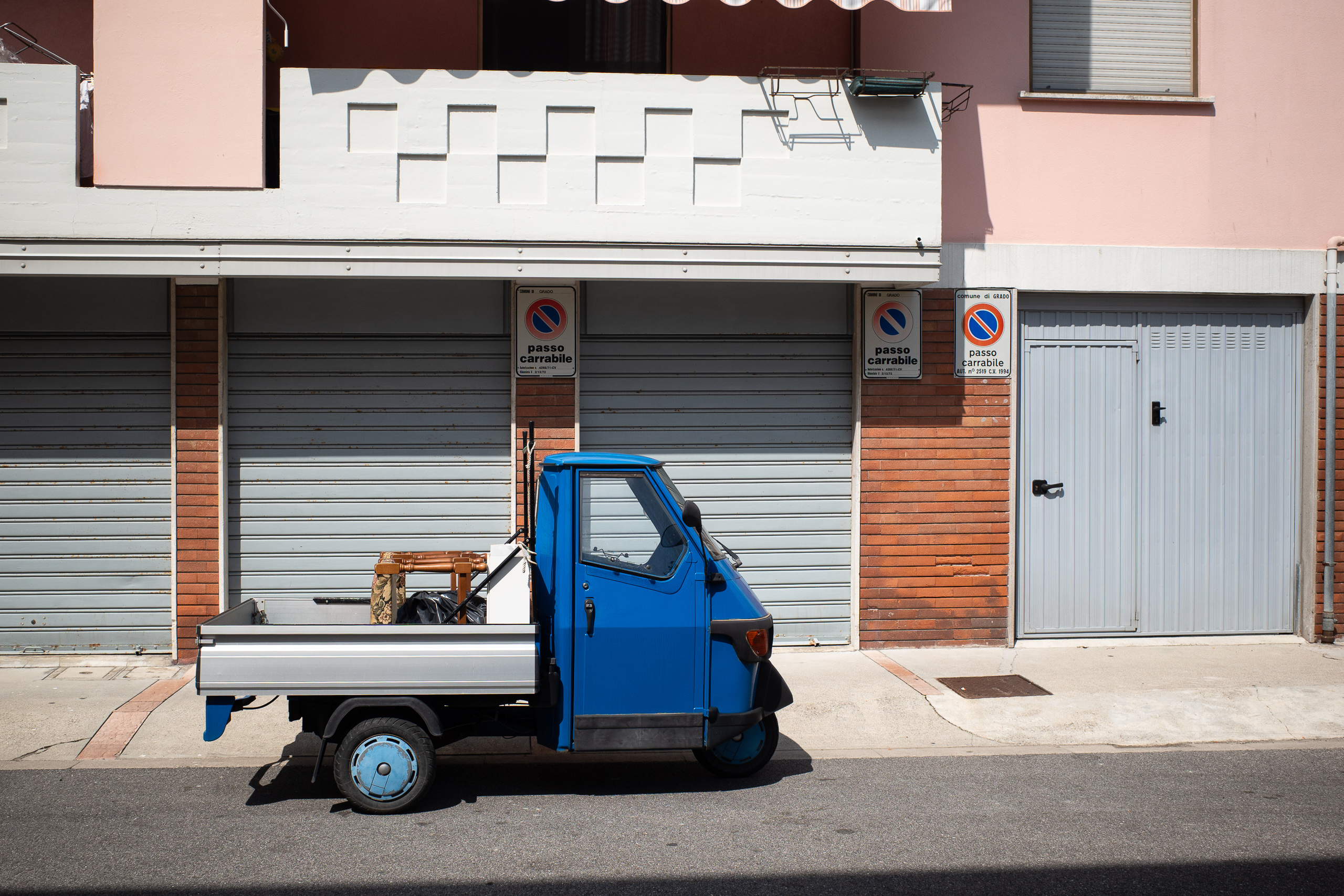 Eine blaue Ape vor den Garagentoren, comune di Grado